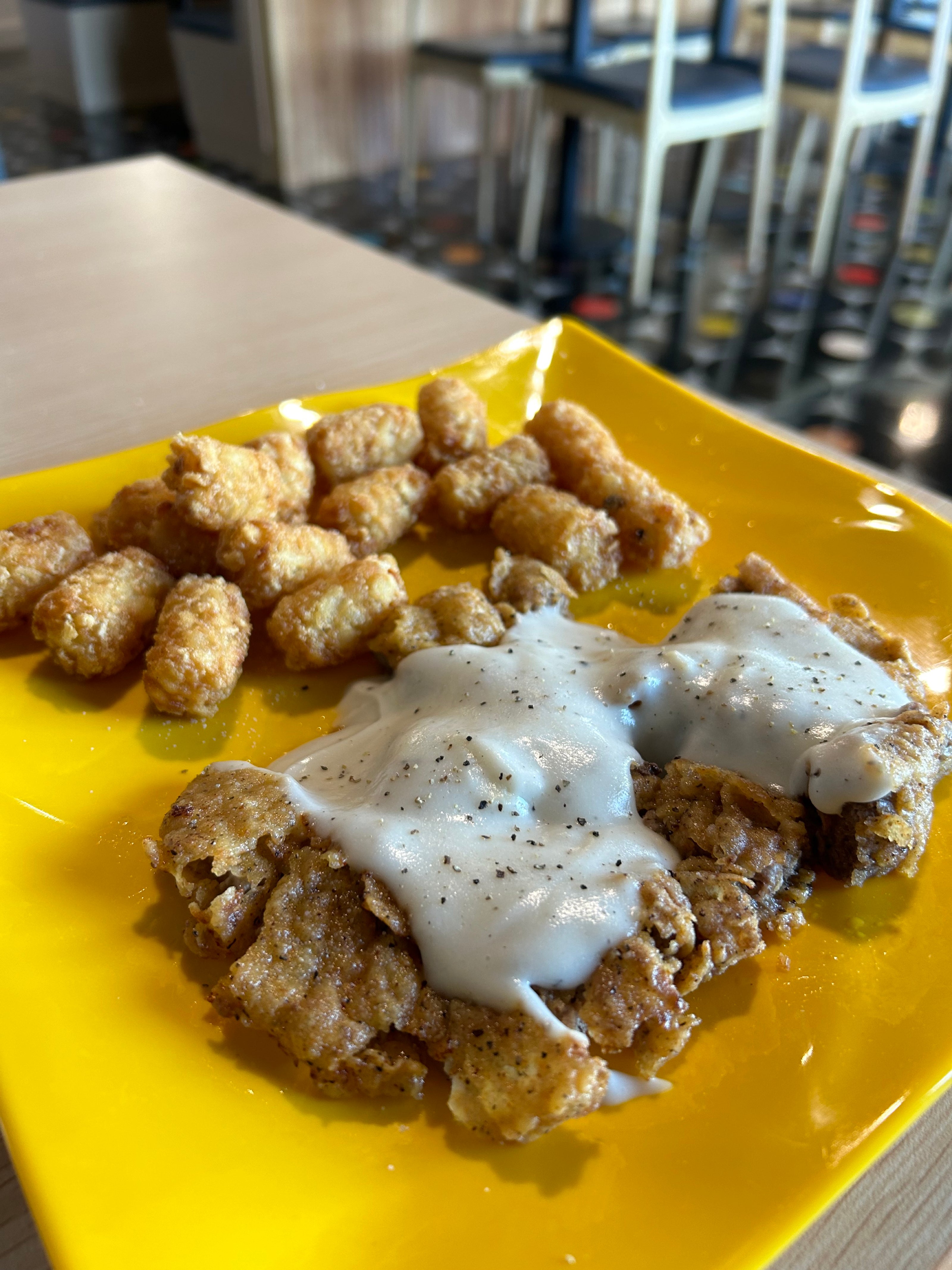 Yellow plate of country fried steak with tater tots at Patty’s.