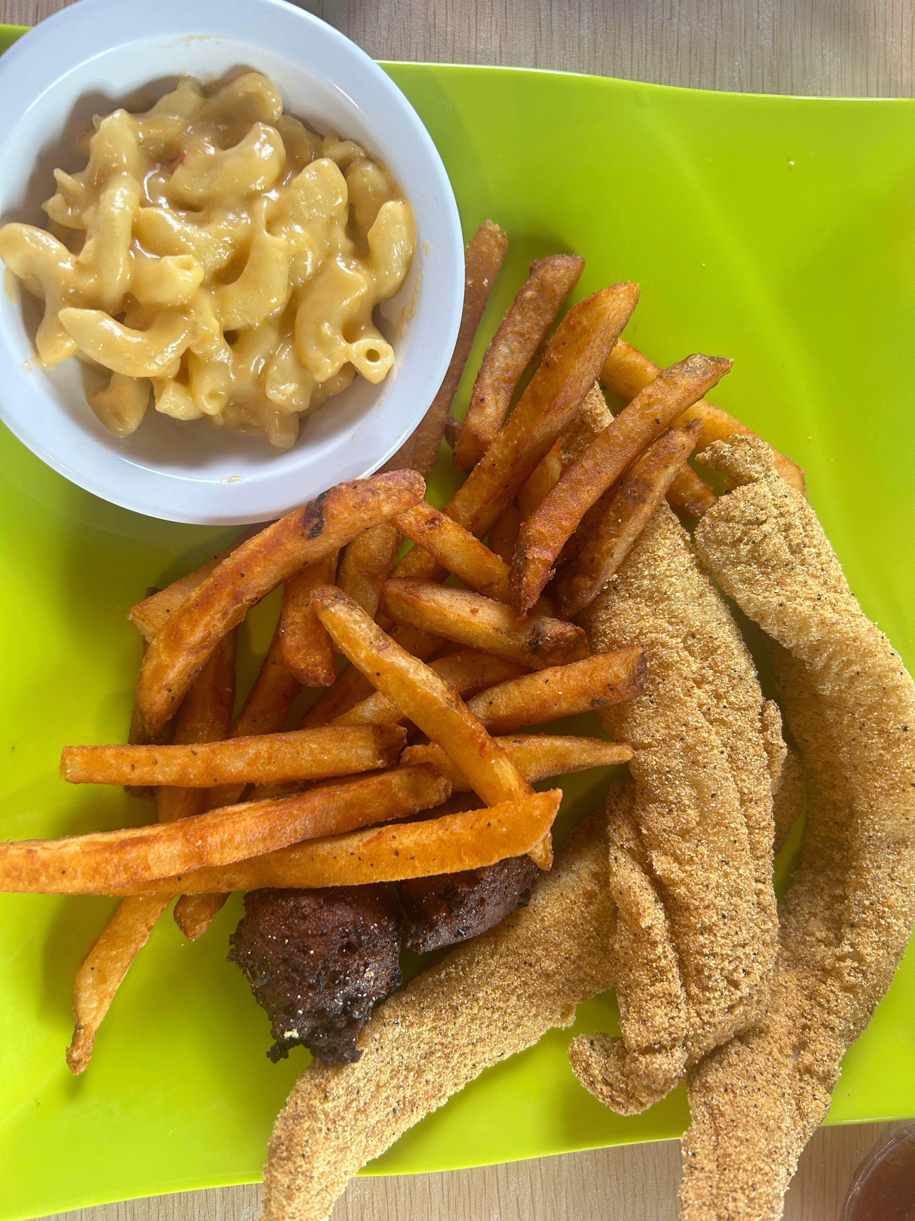Green plate of fried fish, hush puppies, cajun fries, and mac and cheese at Patty's.